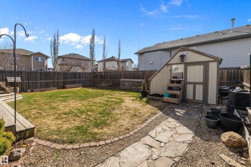 Expansive backyard featuring a central lawn, a wooden privacy fence, and a stone walkway - 992 Regency Drive, Sherwood Park, AB - Outdoor