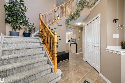 Foyer featuring a two-story staircase with light wood banisters, carpeted stairs, and neutral wall tones - 992 Regency Drive, Sherwood Park, AB - Indoor Photo Showing Other Room