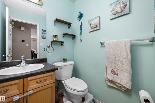 Bathroom featuring a vanity with a white oval sink, dark countertop, and warm-toned wood cabinetry - 992 Regency Drive, Sherwood Park, AB - Indoor Photo Showing Bathroom