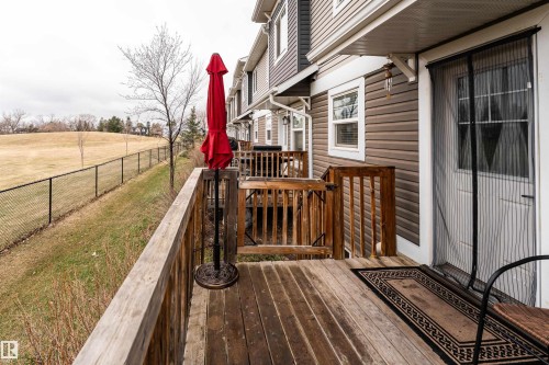 Rear wooden deck featuring a fenced green space and horizontal siding exterior - 15 5203 149 Avenue, Edmonton, AB - Outdoor With Deck Patio Veranda
