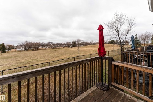 Wood deck featuring a perimeter railing and expansive green space beyond - 15 5203 149 Avenue, Edmonton, AB - Outdoor
