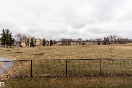Expansive green space featuring a chain-link fence, mature trees, and a paved pathway - 15 5203 149 Avenue, Edmonton, AB - Outdoor With View