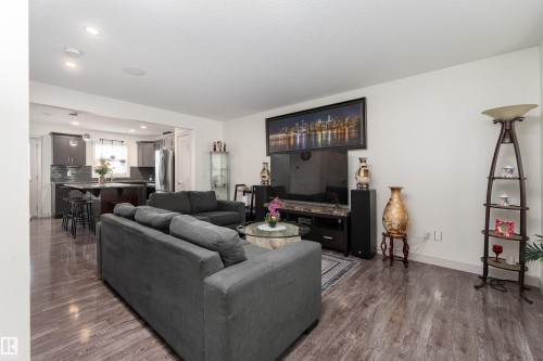 Open-concept living space featuring wood-finish flooring, recessed lighting, and a kitchen with dark cabinetry and stainless steel appliances - 15 5203 149 Avenue, Edmonton, AB - Indoor Photo Showing Living Room