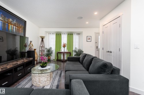 Spacious living area featuring dark wood-finish flooring, recessed lighting, and a prominent bay window - 15 5203 149 Avenue, Edmonton, AB - Indoor Photo Showing Living Room