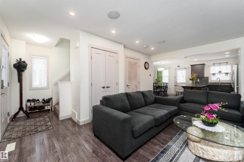 Open-concept living space featuring wood-finish flooring, recessed lighting, white trim, and a kitchen with dark cabinetry and a central island - 15 5203 149 Avenue, Edmonton, AB - Indoor Photo Showing Living Room