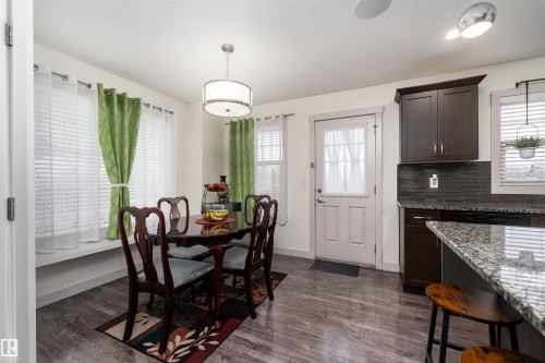 Dining area featuring wood-finish flooring, a contemporary drum pendant light, and multiple windows with blinds - 15 5203 149 Avenue, Edmonton, AB - Indoor Photo Showing Other Room