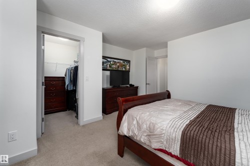 Carpeted bedroom with neutral wall tones and a walk-in closet featuring wire shelving - 15 5203 149 Avenue, Edmonton, AB - Indoor Photo Showing Bedroom