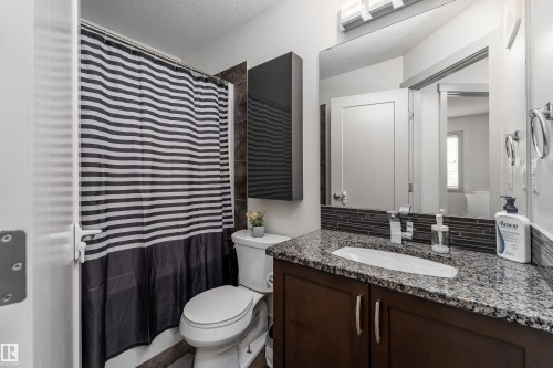 Bathroom featuring a vanity with granite countertop, integrated sink, and dark wood cabinetry - 15 5203 149 Avenue, Edmonton, AB - Indoor Photo Showing Bathroom