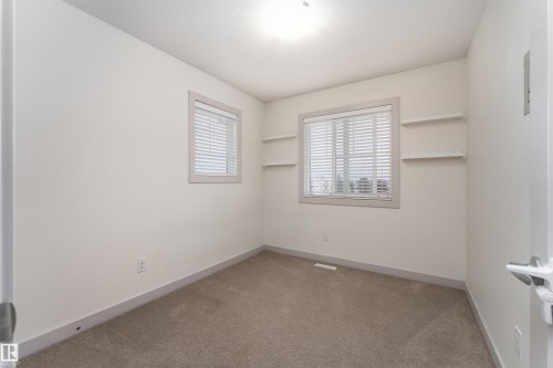 Neutral wall paint with carpet flooring, a window featuring horizontal blinds, and built-in shelving - 15 5203 149 Avenue, Edmonton, AB - Indoor Photo Showing Other Room