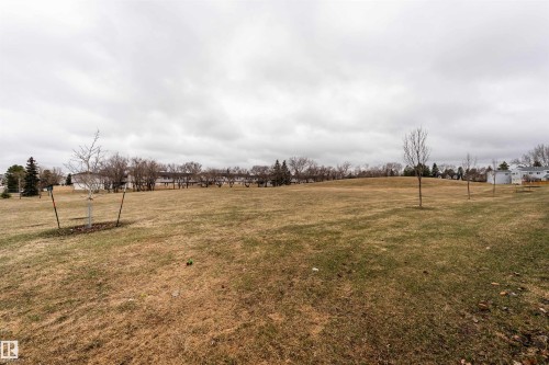 Expansive grassy area with a gentle slope and scattered young trees - 15 5203 149 Avenue, Edmonton, AB - Outdoor With View