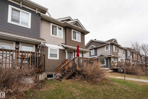 Townhouse exterior featuring multi-toned horizontal siding, white trim windows, and pitched shingle roofs - 15 5203 149 Avenue, Edmonton, AB - Outdoor With Deck Patio Veranda