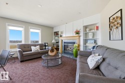Common area featuring a fireplace with a wood mantel, integrated shelving, and two large windows - 