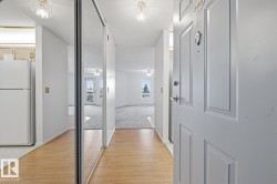 Entryway featuring wood-finish flooring, a full-length mirrored closet door, and a paneled entry door with a door knocker and peep hole - 