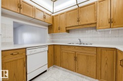 Kitchen featuring extensive wood-finish cabinetry, white countertops, tile backsplash, and a double basin stainless steel sink - 