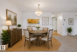 Dining area featuring a contemporary chandelier, wood-finish flooring, and a pass-through opening to the kitchen - 
