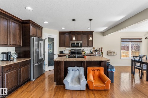 Kitchen featuring wood-finish flooring, dark wood cabinetry, and a central island with a granite-style countertop - 41 Heron Crescent, Spruce Grove, AB - Indoor Photo Showing Kitchen