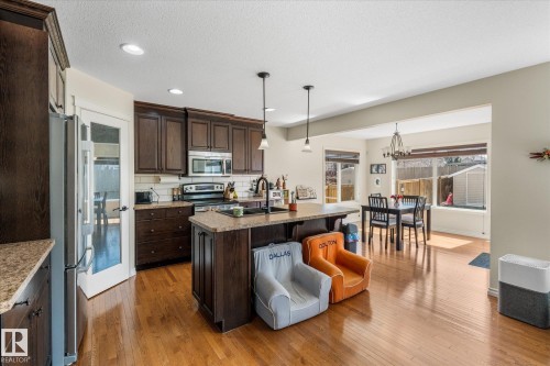 Kitchen featuring dark wood cabinetry, stainless steel appliances, a center island with pendant lighting, and light-toned countertops - 41 Heron Crescent, Spruce Grove, AB - Indoor Photo Showing Kitchen