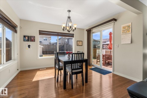 Dining space featuring wood-finish flooring, multiple windows with blinds, a sliding glass door, a built-in chandelier, and a wood deck - 41 Heron Crescent, Spruce Grove, AB - Indoor Photo Showing Dining Room