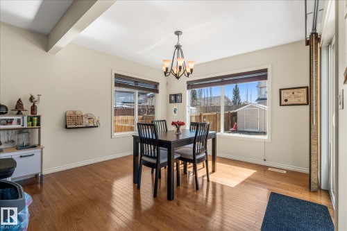 Dining area featuring wood-finish flooring, two large windows with blinds, a ceiling-mounted chandelier, and neutral wall paint - 41 Heron Crescent, Spruce Grove, AB - Indoor Photo Showing Dining Room