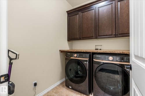 Laundry area featuring dark wood-finish cabinetry, a light-toned countertop, and tiled flooring - 41 Heron Crescent, Spruce Grove, AB - Indoor Photo Showing Laundry Room