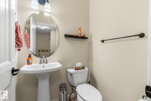 Pedestal sink with chrome faucet, complemented by an oval mirror and two-light vanity fixture - 41 Heron Crescent, Spruce Grove, AB - Indoor Photo Showing Bathroom