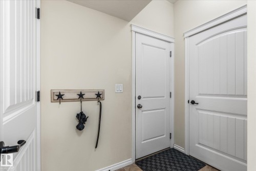 Entryway featuring white paneled doors with dark hardware, crown molding, and neutral wall tones - 41 Heron Crescent, Spruce Grove, AB - Indoor Photo Showing Other Room