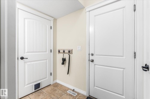 Entryway featuring ceramic tile flooring, a white paneled door with matte black hardware, and an additional white paneled door with chrome hardware - 41 Heron Crescent, Spruce Grove, AB - Indoor Photo Showing Other Room