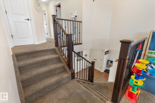 Carpeted staircase featuring wood newel posts and wrought iron balusters - 41 Heron Crescent, Spruce Grove, AB - Indoor Photo Showing Other Room