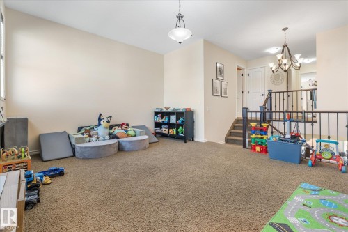 Spacious carpeted room featuring a sloped ceiling, light beige wall paint, a multi-pane window, and a built-in black storage shelf - 41 Heron Crescent, Spruce Grove, AB - Indoor Photo Showing Other Room
