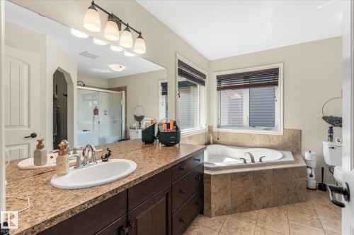 Bathroom featuring a corner soaking tub, dual windows with blinds, a vanity with a large mirror, and a glass-enclosed shower - 41 Heron Crescent, Spruce Grove, AB - Indoor Photo Showing Bathroom