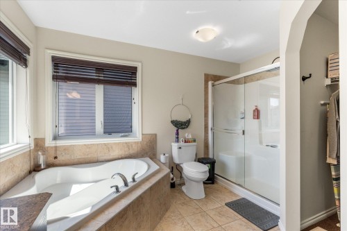 Enclosed shower with glass doors and a built-in tub featuring deck-mounted fixtures - 41 Heron Crescent, Spruce Grove, AB - Indoor Photo Showing Bathroom