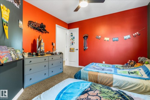 Carpeted room featuring a white door, a ceiling fan with light, and a built-in shelf - 41 Heron Crescent, Spruce Grove, AB - Indoor Photo Showing Bedroom