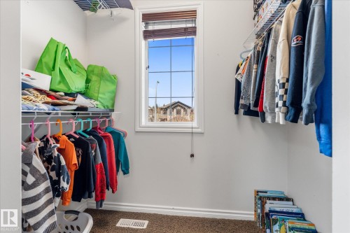 Walk-in closet featuring a framed window with blinds, carpeted flooring, and white wire shelving with hanging rods - 41 Heron Crescent, Spruce Grove, AB - Indoor With Storage