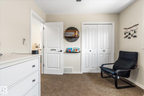 Neutral-toned room featuring a textured carpet, white bi-fold closet doors, and a white paneled interior door - 41 Heron Crescent, Spruce Grove, AB - Indoor