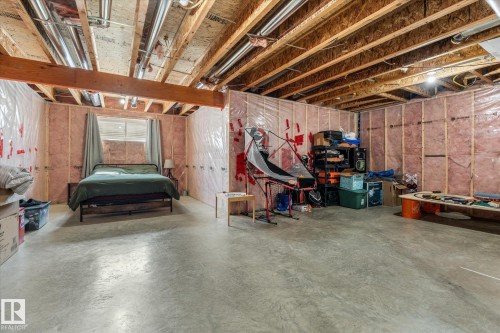 Unfinished basement space featuring exposed wood joists and structural beams, pink insulation, and a concrete floor - 41 Heron Crescent, Spruce Grove, AB - Indoor Photo Showing Basement