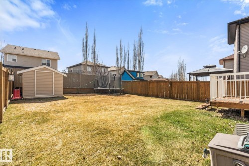 Spacious backyard featuring a wooden privacy fence, a detached storage shed, and an elevated wooden deck with white railings - 41 Heron Crescent, Spruce Grove, AB - Outdoor