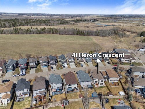 Aerial perspective showcasing a residential neighborhood bordering expansive undeveloped land - 41 Heron Crescent, Spruce Grove, AB - Outdoor With View