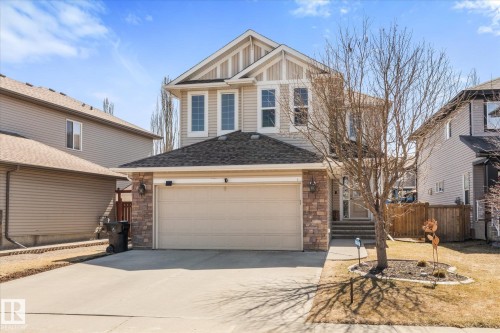 Two-story residential exterior featuring a light-colored siding, a stone veneer accent, and a single attached garage with a paved driveway - 41 Heron Crescent, Spruce Grove, AB - Outdoor