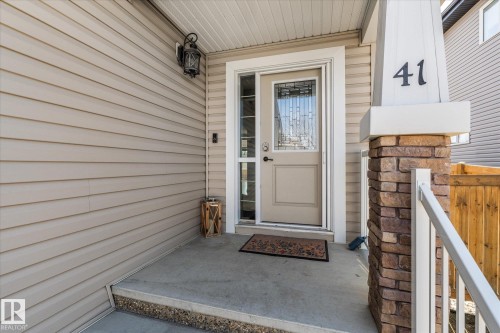 Front entry featuring a stone-accented pillar, beige siding, white trim, and a decorative glass door - 41 Heron Crescent, Spruce Grove, AB - Outdoor With Exterior