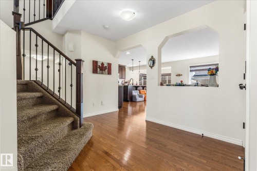 Entryway featuring wood-finish flooring, a carpeted staircase with a dark wood handrail and wrought iron balusters, and a decorative arched wall opening - 41 Heron Crescent, Spruce Grove, AB - Indoor Photo Showing Other Room