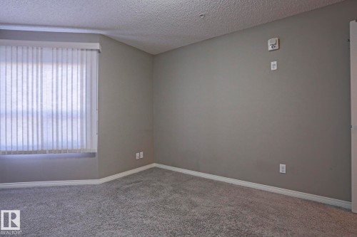 Room with neutral gray wall paint, light gray carpeting, and white baseboards - 201 1520 Hammond Gate Gate, Edmonton, AB - Indoor Photo Showing Other Room