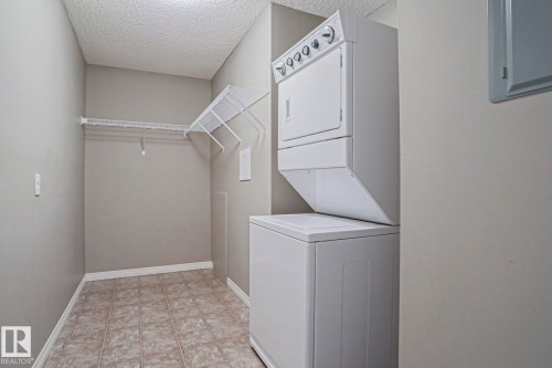 Dedicated laundry area featuring a stacked washer and dryer unit - 201 1520 Hammond Gate Gate, Edmonton, AB - Indoor Photo Showing Laundry Room