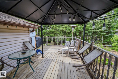 Wood-finish deck featuring a dark metal gazebo with string lighting, wood railing, and surrounding mature trees - 400 60501 Range Road 120, Rural St. Paul County, AB - Outdoor With Deck Patio Veranda With Exterior