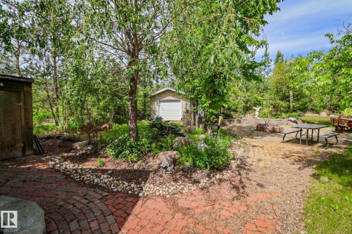 Expansive outdoor area featuring a brick paver patio, mature trees, and a detached storage shed - 400 60501 Range Road 120, Rural St. Paul County, AB - Outdoor
