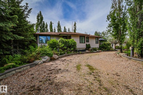 Ranch-style residence featuring light-colored siding, a brown shingle roof, and mature perimeter trees - 400 60501 Range Road 120, Rural St. Paul County, AB - Outdoor