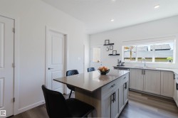 Kitchen featuring a central island with countertop seating, light wood-finish cabinetry, a large window, recessed lighting, and wood-finish flooring - 