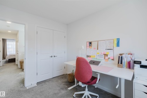 Carpeted room with white walls, featuring a built-in closet with double doors, and an open doorway revealing a hallway - 5237 Edgemont Boulevard, Edmonton, AB - Indoor Photo Showing Office