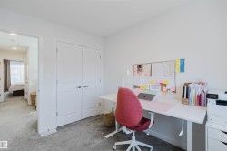 Carpeted room with white walls, featuring a built-in closet with double doors, and an open doorway revealing a hallway - 