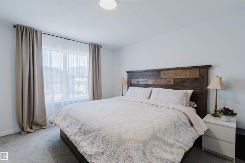 Bedroom featuring a large window with sheer and blackout curtains, light gray carpet flooring, white walls, and a recessed ceiling light fixture - 5237 Edgemont Boulevard, Edmonton, AB - Indoor Photo Showing Bedroom