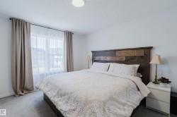 Bedroom featuring a large window with sheer and blackout curtains, light gray carpet flooring, white walls, and a recessed ceiling light fixture - 